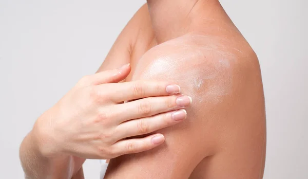Cuidado com o corpo. Mulher se preocupa com o ombro aplicando creme cosmético — Fotografia de Stock