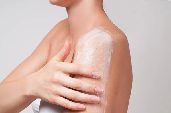Cuidado com o corpo. Mulher se preocupa com o ombro aplicando creme cosmético — Fotografia de Stock