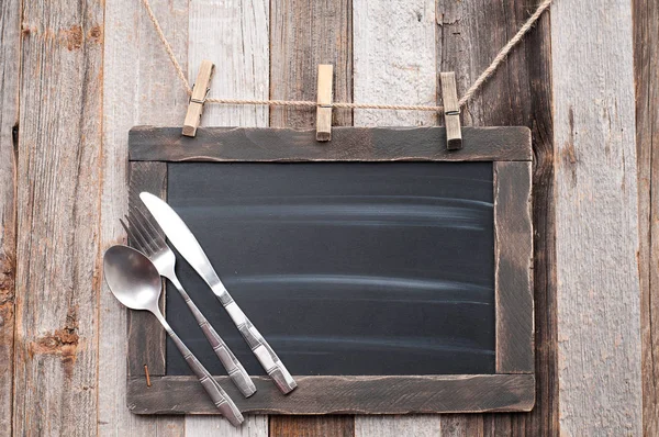 Menu blackboard with fork, spoon and knife on wood background