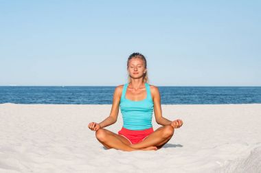 Kadın plajda yoga yapıyor.