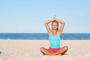 Kadın plajda yoga yapıyor.