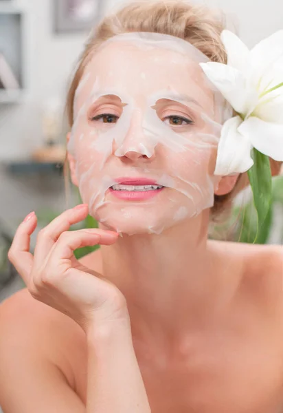 Spa salon. Beautiful woman with facial mask at beauty salon — Stock Photo, Image