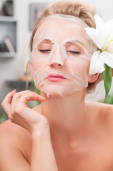 Spa salon. Beautiful woman with facial mask at beauty salon — Stock Photo, Image