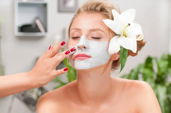 Spa salon. Beautiful woman with clay facial mask at beauty salon — Stock Photo, Image