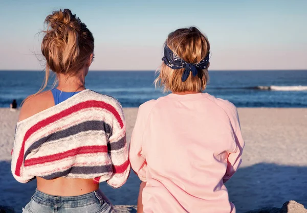 Two young girls, best friends sitting together on the beach at s — Stock Photo, Image