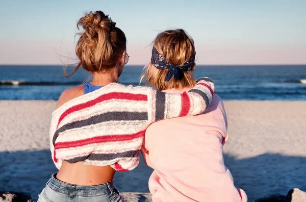 Zwei junge Mädchen, beste Freundinnen sitzen zusammen am Strand bei s — Stockfoto