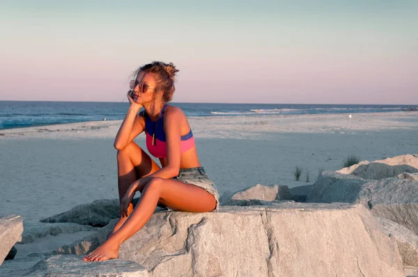 Mooie jonge vrouw op het strand bij zonsondergang. — Stockfoto