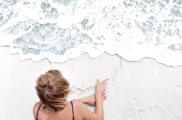 Ragazza sta dipingendo cuore sulla sabbia . — Foto Stock