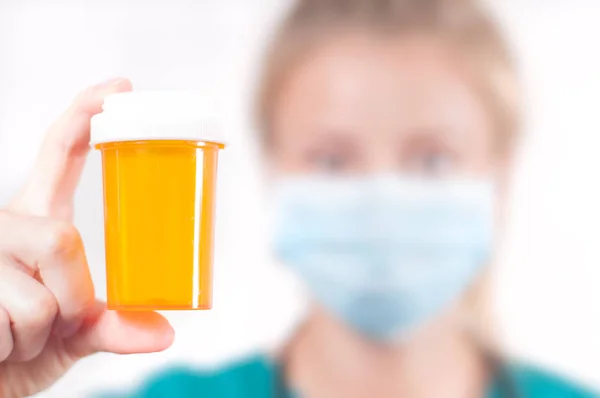 Médica, enfermeira segurando uma garrafa de pílulas em fundo branco . — Fotografia de Stock