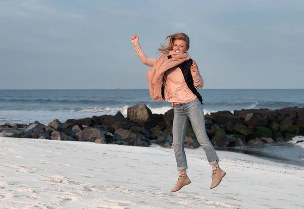 Happy girl jumping playfully on beach in autumn. — Stock Photo, Image