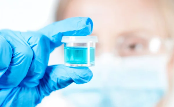 Químico em óculos de proteção segurando tubo de ensaio com reagente em laboratório — Fotografia de Stock