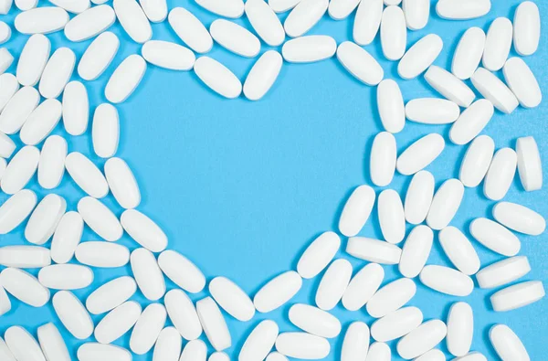 파란색 배경에 흰색 알 약의 심장 — 스톡 사진