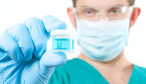 Médico em óculos de proteção segurando tubo de ensaio com reagente em laboratório — Fotografia de Stock