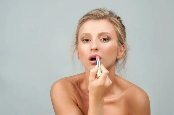 Beautiful woman with fresh skin is holding lipstick. — Stock Photo, Image