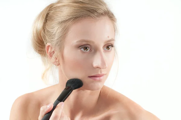 Hermosa mujer que aplica cosméticos secos en la cara usando cepillo de maquillaje . — Foto de Stock