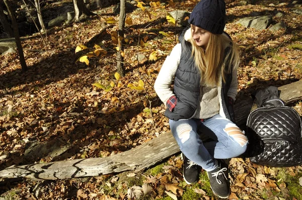 Lány ül az őszi erdő, a hegyek között. Kirándulás és utazótáska — Stock Fotó