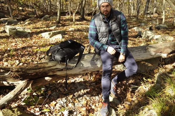 El hombre está sentado en el bosque de otoño en las montañas. Senderismo y viajes — Foto de Stock