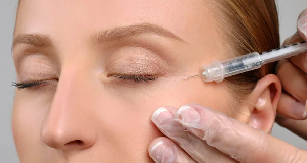 A mulher está a receber uma injecção de botox. Tratamento anti-envelhecimento e lifting facial. Tratamento cosmético e cirurgia plástica — Fotografia de Stock