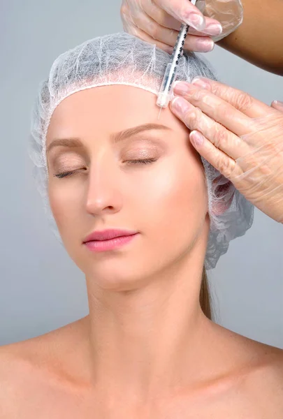 La mujer está recibiendo la inyección sobre la ceja. Tratamiento antienvejecimiento y lifting facial. Tratamiento cosmético y cirugía plástica — Foto de Stock