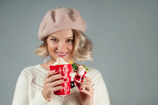 Χριστούγεννα και Πρωτοχρονιά. Γυναίκα σε ζεστό καπέλο κρατώντας ένα φλιτζάνι καφέ. — Φωτογραφία Αρχείου