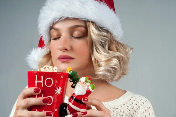 Christmas and New Year.  Woman in santa's hat is holding a cup of coffee. — Stock Photo, Image