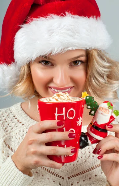 クリスマスと新年。サンタさんの帽子の女は一杯のコーヒーを保持しています。. — ストック写真
