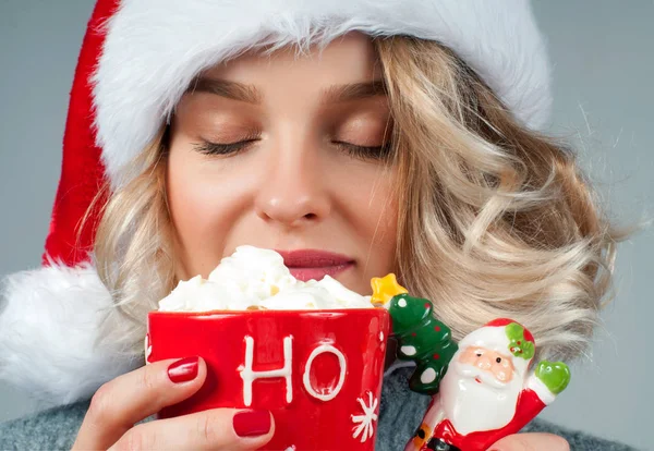 Christmas and New Year.  Woman in santa's hat is holding a cup of coffee. — Stock Photo, Image