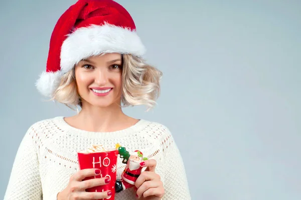 Christmas and New Year.  Woman in santa's hat is holding a cup of coffee. — Stock Photo, Image