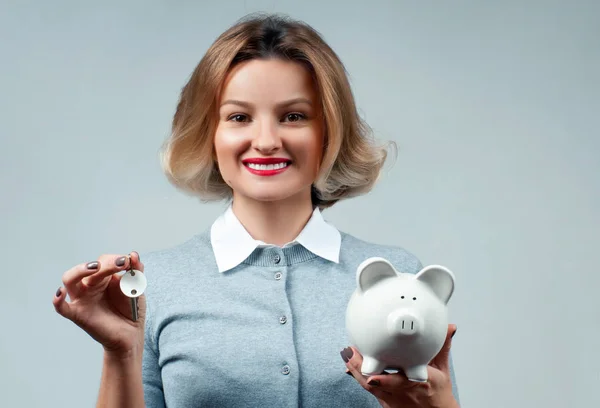 Happy business showing keys and piggy bank — Stock Photo, Image
