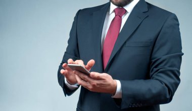 Takım elbiseli bir işadamı akıllı telefon kullanıyor. 