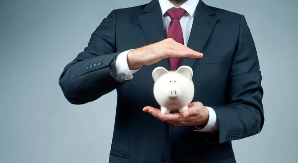 Koncept úspory financí. Podnikatel v obleku drží prasátko. — Stock fotografie