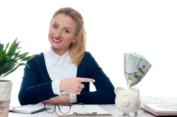 Woman pointing piggy bank with bunch of money banknotes — Stock Photo, Image