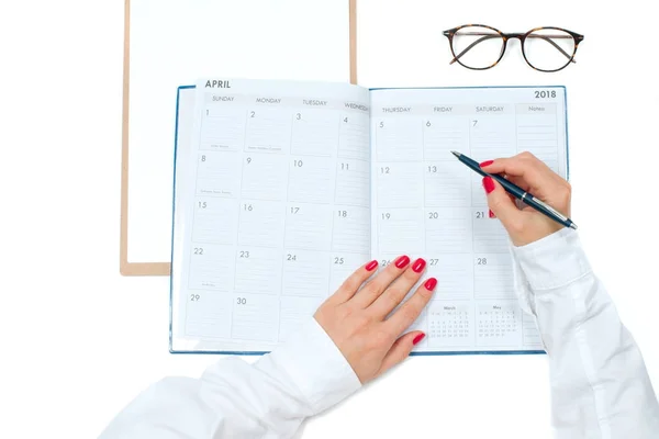 Felülnézet íróasztal. Munkaterület-a női kéz, a vágólapra, a naptár és a szemüveg — Stock Fotó
