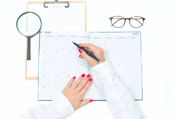 Escritorio de oficina con vista superior. Espacio de trabajo con manos femeninas, portapapeles, calendario y gafas —  Fotos de Stock