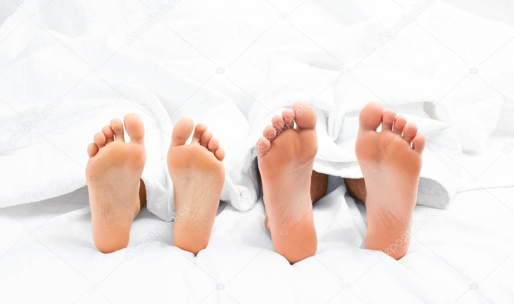 Close up of the feet of a couple on the bed.