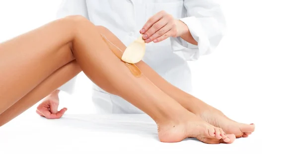 Centrum Spa. Kosmetologia zabiegiem depilacji. Kosmetyczka woskowanie kobiece nogi — Zdjęcie stockowe