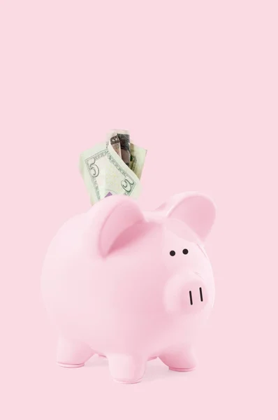Billetes en alcancía y dólar sobre fondo rosa pastel — Foto de Stock