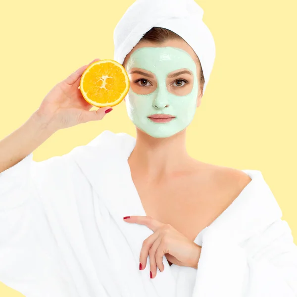 Beautiful woman with clay mask on pastel yellow background. Beauty and spa — Stock Photo, Image