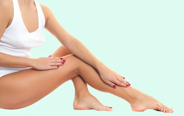 Жіночі ноги з гладкою шкірою після депіляції на пастельному зеленому тлі . — стокове фото