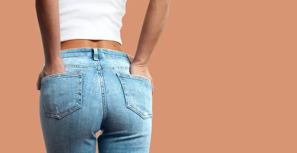 Fundo feminino em jeans apertados no fundo pastel — Fotografia de Stock