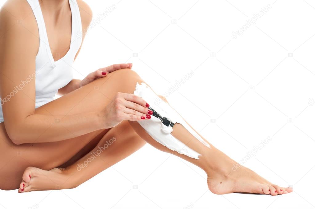 Woman shaves her leg on white background