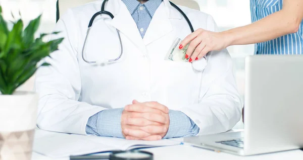 Mano femenina poniendo dinero en el bolsillo del médico . — Foto de Stock