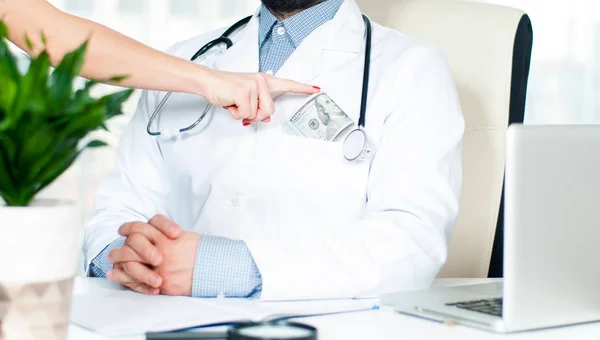 Mano femenina poniendo dinero en el bolsillo del médico . — Foto de Stock