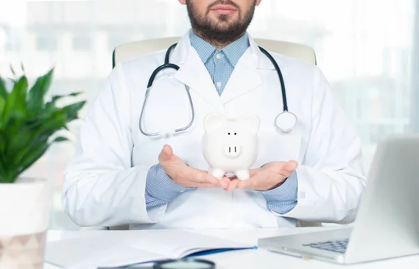 Médico con estetoscopio sosteniendo alcancía . — Foto de Stock