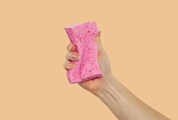 Woman's hand, holding a sponge on pastel background — Stock Photo, Image