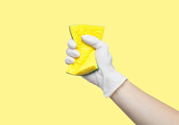 Rękę, trzymając gąbka na pastelowe tło żółty — Zdjęcie stockowe