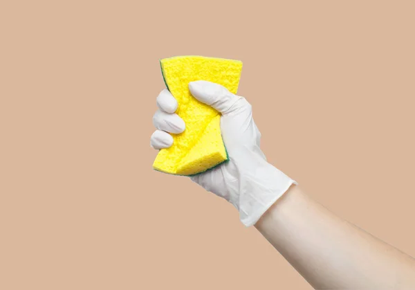 Rękę, trzymając gąbka na pastelowe tło żółty — Zdjęcie stockowe