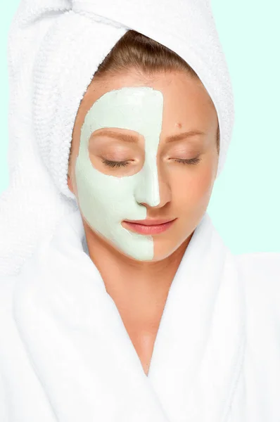 Beauty Spa. Woman applying clay mask on face. Pastel background — Stock Photo, Image