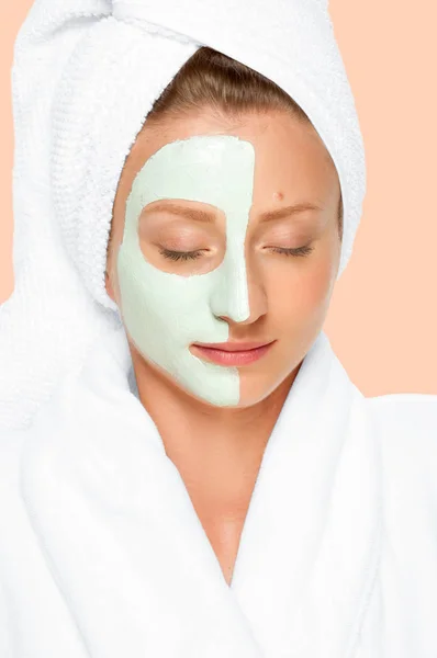 Beauty Spa. Mujer que aplica máscara de arcilla en la cara. Fondo de pastel —  Fotos de Stock