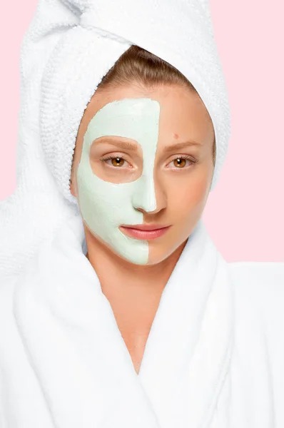 Beauty Spa. Woman applying clay mask on face. Pastel background — Stock Photo, Image